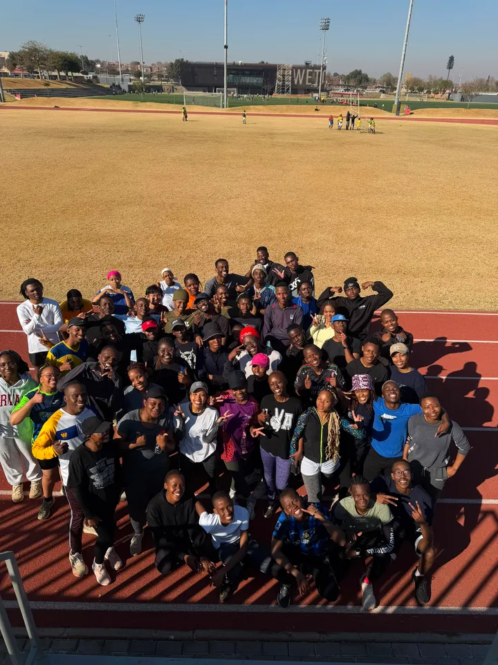 A large group of students in workout gear on the athletics track after a session