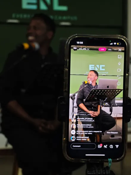 A phone on a gimbal live-streaming a campus session, the speaker in shot on screen